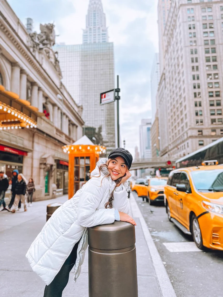 Camila em Nova York, com táxis amarelos ao fundo