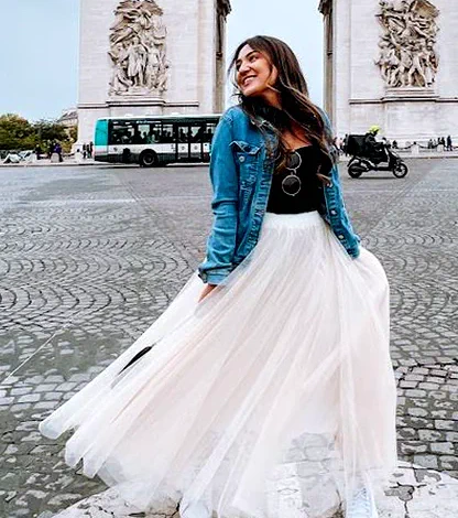 Camila de jaqueta jeans e saia de tule diante do Arco do Triunfo