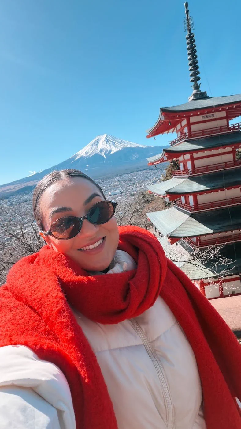 Camila em selfie com o Monte Fuji e um pagode ao fundo