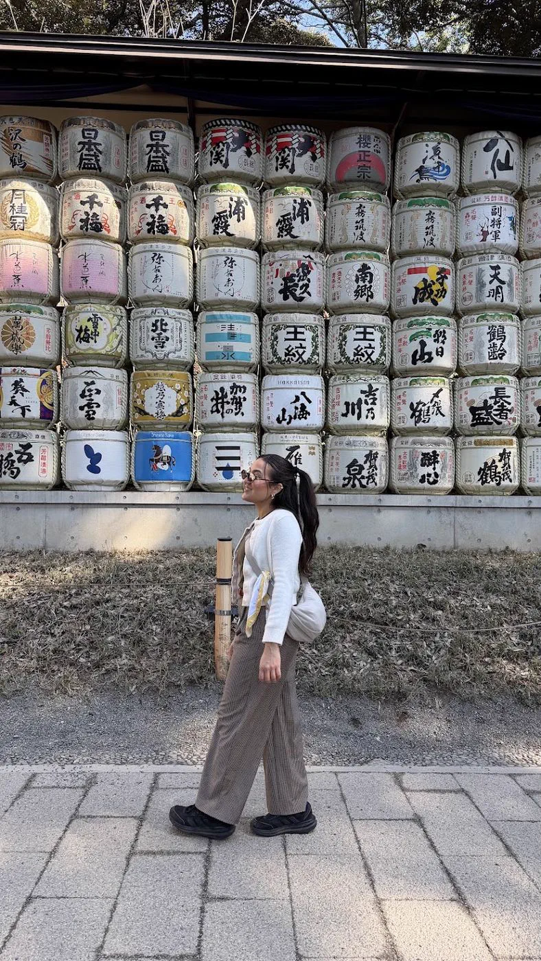 Camila caminhando diante de barris de saquê decorados, em Tokyo