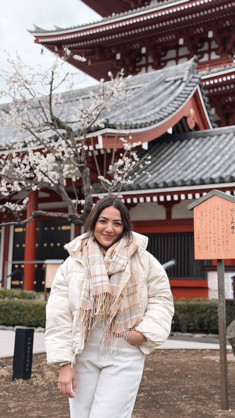 Camila de casaco branco diante de um templo em Tokyo